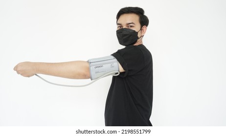 Young Asian Man While Having His Blood Pressure Checked Using A Mask