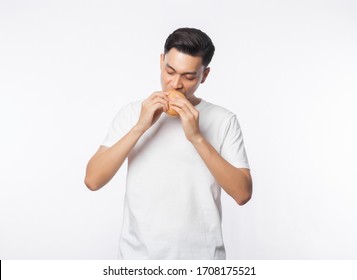 Young Asian Man In White T-shirt Eating Hamburger With Happy Face Isolated On White Background.