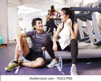 young asian man and woman chatting in gym while taking a break. - Powered by Shutterstock