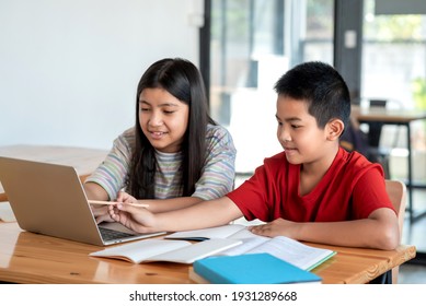 Young Asian man and woman students work together using a laptop and take notes in the classroom. - Powered by Shutterstock