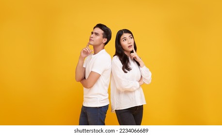 young asian man and woman thinking and touching chin while looking aside isolated on yellow background. - Shutterstock ID 2234066689