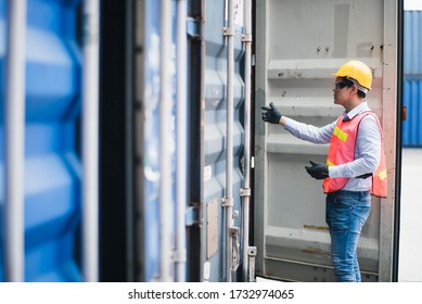 Young Asian Man Worker Foreman Open The Door Of Shipping Containers At Commercial Shipping Dock Felling Serious. Engineer Inspection. Cargo Freight Ship Import Export Concept.