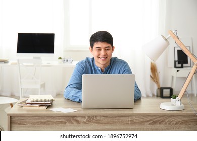 Young Asian Man Working On Laptop At Home