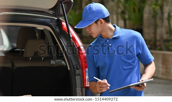 Young asian man working with post man, Delivery\
man checking with boxes in\
car.