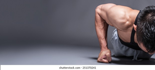 Young Asian Man Workout Over Grey Background With Copy-space