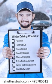 Young Asian Mechanic Holding A Clipboard And Showing A Winter Driving Tips, Shot Outdoors