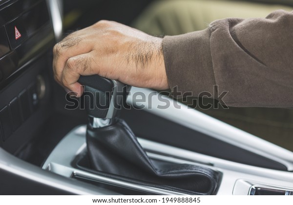 Young asian men getting new car and his hand control\
the stick shift transmission in luxury car. Male hand changing gear\
driving car.