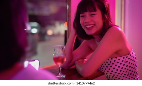 Young asian millennial teen woman talking and drinking cocktail with friend in neon night club, lifestyle background - Powered by Shutterstock