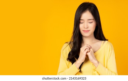 Young Asian Millennial Woman Hold Hands On Heart Chest Beautiful Girl Get Grateful And Thankful Happy Lady Show Gratitude, Love And Care, Pray Or Make A Wish Religion And Faith Concept She Closed Eyes