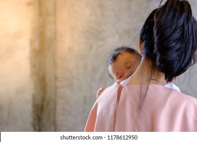 Young Asian Mom Carry And Singing A Lullabies For Her Little Son To Sleep, So Sweet,on Concrete Wall Loft Style Background.