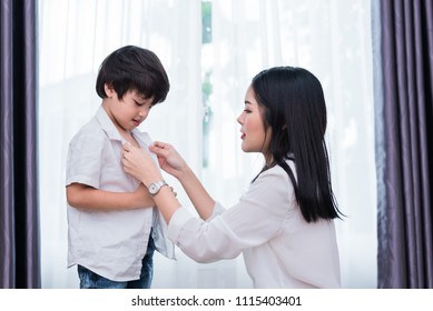 Young Asian Mom Dressed Up Son Outfits For Preparing Go To School. Mother And Son Concept. Happy Family And Home Sweet Home Theme. Preschool And Back To School Theme.