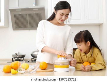 Young Asian Mom Making Fresh Juice For Daughter