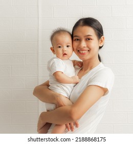 Young Asian Mom And Sweet Baby Daughter, Health Care Family Love Together. Asia Mother's Day Concept. Looking To Camera.