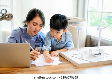 Young Asian Mother Is An Architect Spending Time With Her Little Kid Son Practicing Pencil Drawing And Writing On Paper At Home While Multitasking. Mother Helping Son, Homeschool Concept