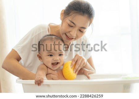 young Asian mother is Bathing with her newborn baby In Bathtub at home.Concept of newborn,baby,parenthood,motherhood,childhood,New life,maternity,love,new family member