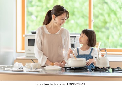 Young Asian Mother And Daughter Cooking At Kitchen