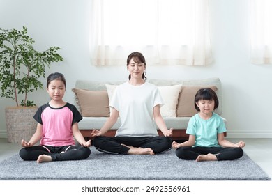 young asian mother and daughter doing yoga together in living room - Powered by Shutterstock