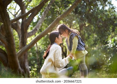 young asian mother and daughter enjoying a good time outdoors in city park