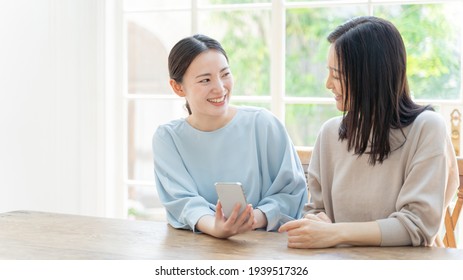 Young Asian Mother And Daughter Using Smart Phone In The Living Room