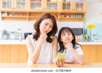 Young Asian Mother And Daughter,smart Phone, Think