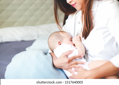 Young Asian Mother Feeding Breast Her Newborn Baby At Home With Copy Space For Texture. Happy Healthy Mom And Son