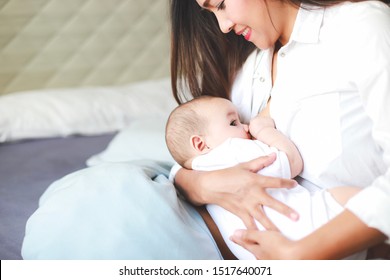 Young Asian Mother Feeding Breast Her Newborn Baby At Home With Copy Space For Texture. Happy Healthy Mom And Son