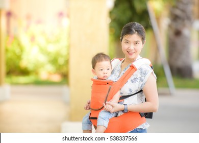 A Young Asian Mother With Her Baby Boy In A Baby Carrier