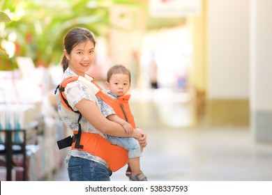 A Young Asian Mother With Her Baby Boy In A Baby Carrier
