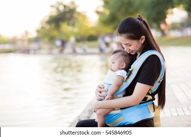 A Young Asian Mother With Her Baby Boy In A Baby Carrier