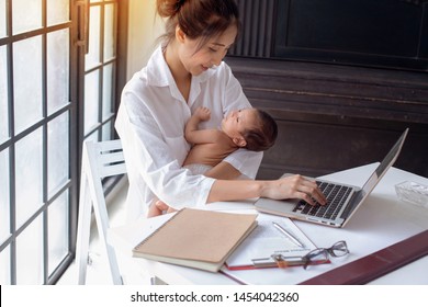 Young Asian Mother Holding Her Newborn Child In Home Office. Mom Nursing Baby, Working Woman With Newborn