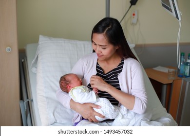 Young Asian Mother Holding Newborn Baby In Her Arms After Giving Birth In Delivery Room At Hospital.