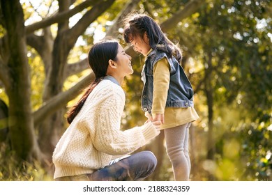 Young Asian Mother And Preschool Daughter Enjoying Nature Having A Good Time Outdoors In Park