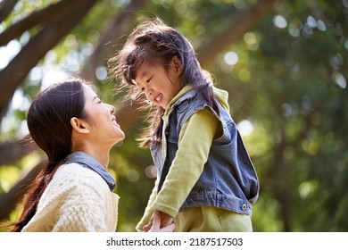 young asian mother sitting on grass in park having a pleasant conversation with cute daughter - Powered by Shutterstock