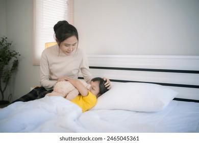 Young Asian mother waked her daughter up from bed in morning. - Powered by Shutterstock