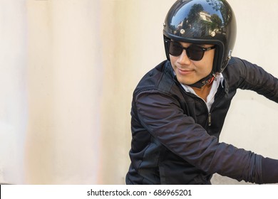 Young Asian Motorcyclist Wearing Black Jacket Is Looking Back While Riding His Motorcycle.