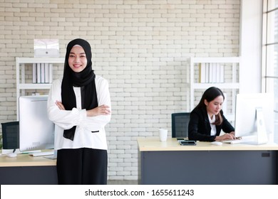 Young Asian Muslim Beautiful Businesswomen Resting In Office Hours But Young Asian Buddhist Lovely Women Still Working Seriously. Bangkok Thailand South East Asia