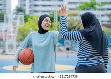 Young asian muslim girl teen wearing hijab going to play basketball on the outdoor court in the morning with determination, Muslim sport concept. - Powered by Shutterstock