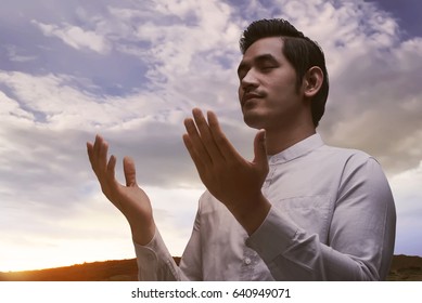 Young Asian Muslim Man Praying Over Sunset Background