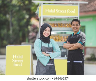 Young Asian Muslim Small Food Stall Owner, Standing Proudly With Her Partner At The Background. Halal Street Food Concept