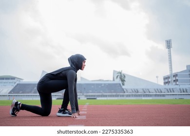 A young asian Muslim woman wearing a black hijab is exercising and running at an outdoor stadium in the morning. Modern Muslim woman concept,  Muslim woman sport concept, Islam - Powered by Shutterstock