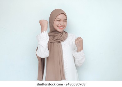 Young Asian Muslim woman wearing hijab, sweet smiling and see camera with happy successful or excited expression, Isolated in gray background. - Powered by Shutterstock