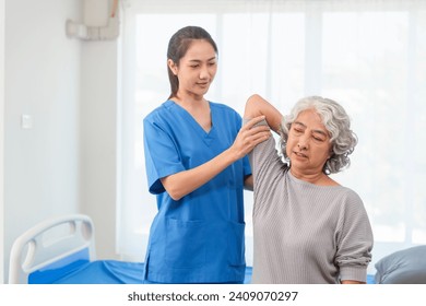 A young Asian nurse is assisting an elderly Asian woman with a grey hair during a physical therapy session. - Powered by Shutterstock