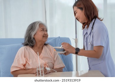 Young Asian nurse feeding breakfast to senior woman patient on bed in hospital ward, elderly care concept - Powered by Shutterstock