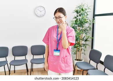 Young Asian Nurse Woman At Medical Waiting Room Pointing To The Eye Watching You Gesture, Suspicious Expression 