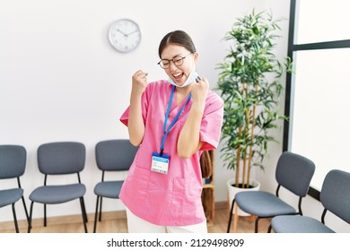 Young Asian Nurse Woman At Medical Waiting Room Very Happy And Excited Doing Winner Gesture With Arms Raised, Smiling And Screaming For Success. Celebration Concept. 