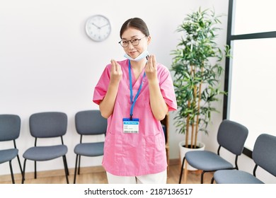 Young Asian Nurse Woman At Medical Waiting Room Doing Money Gesture With Hands, Asking For Salary Payment, Millionaire Business 