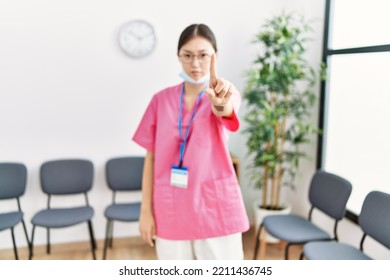 Young Asian Nurse Woman At Medical Waiting Room Pointing With Finger Up And Angry Expression, Showing No Gesture 