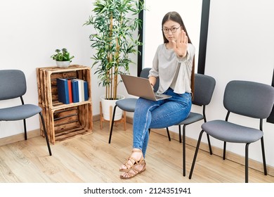 Young Asian Nurse Woman Sitting At Waiting Room Using Laptop With Open Hand Doing Stop Sign With Serious And Confident Expression, Defense Gesture 