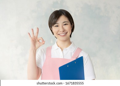 Young Asian Nursery School Teacher Showing OK Sign.