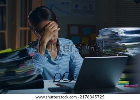 Young Asian office employee feeling tired, fatigue, exhausted while working overtime at night in office
